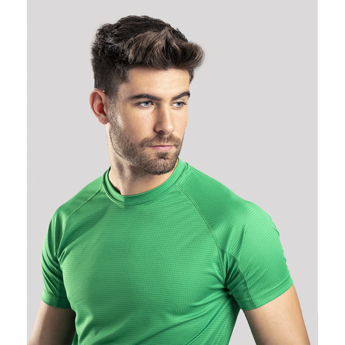 A green Dynamic T-Shirt worn by a man with short hair and a serious expression, presented against a grey background.
