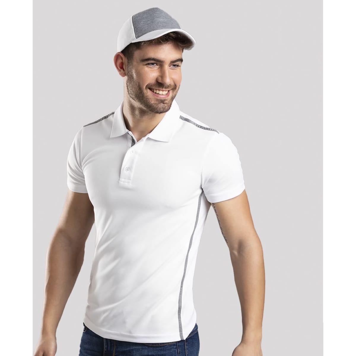 A white polo shirt with grey accents, paired with a matching grey cap, displayed by a smiling man.