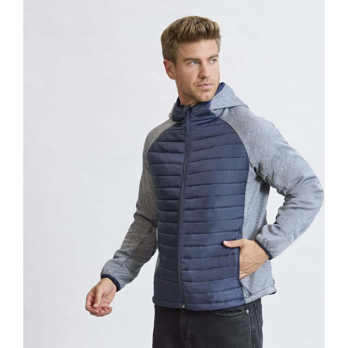 A man wearing a navy and grey soft shell jacket with a hood, featuring a zip front and side pockets.