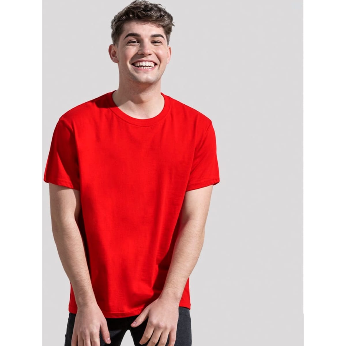 A red organic T-shirt worn by a smiling young man. The shirt has a relaxed fit and features a logo.