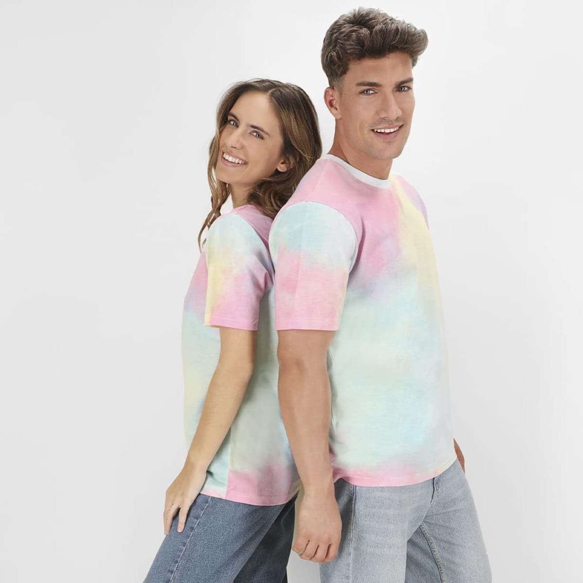A pair of models wearing pastel tie-dye Vega T-Shirts in pink, blue, and green. The shirts feature a logo.
