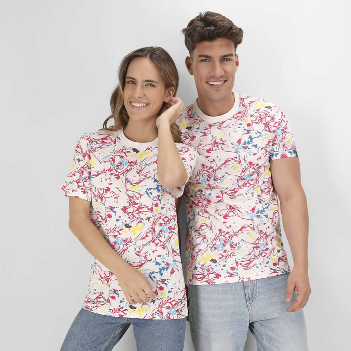 A floral-patterned Helixa T-Shirt in white, featuring bright colours like red, yellow, and blue. It has a logo.