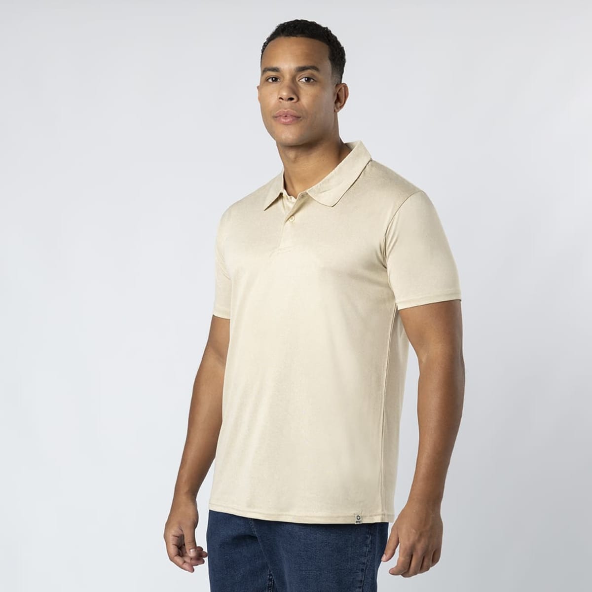 A beige polo shirt with a collar, displayed on a male model against a plain background. There is a logo on the shirt.