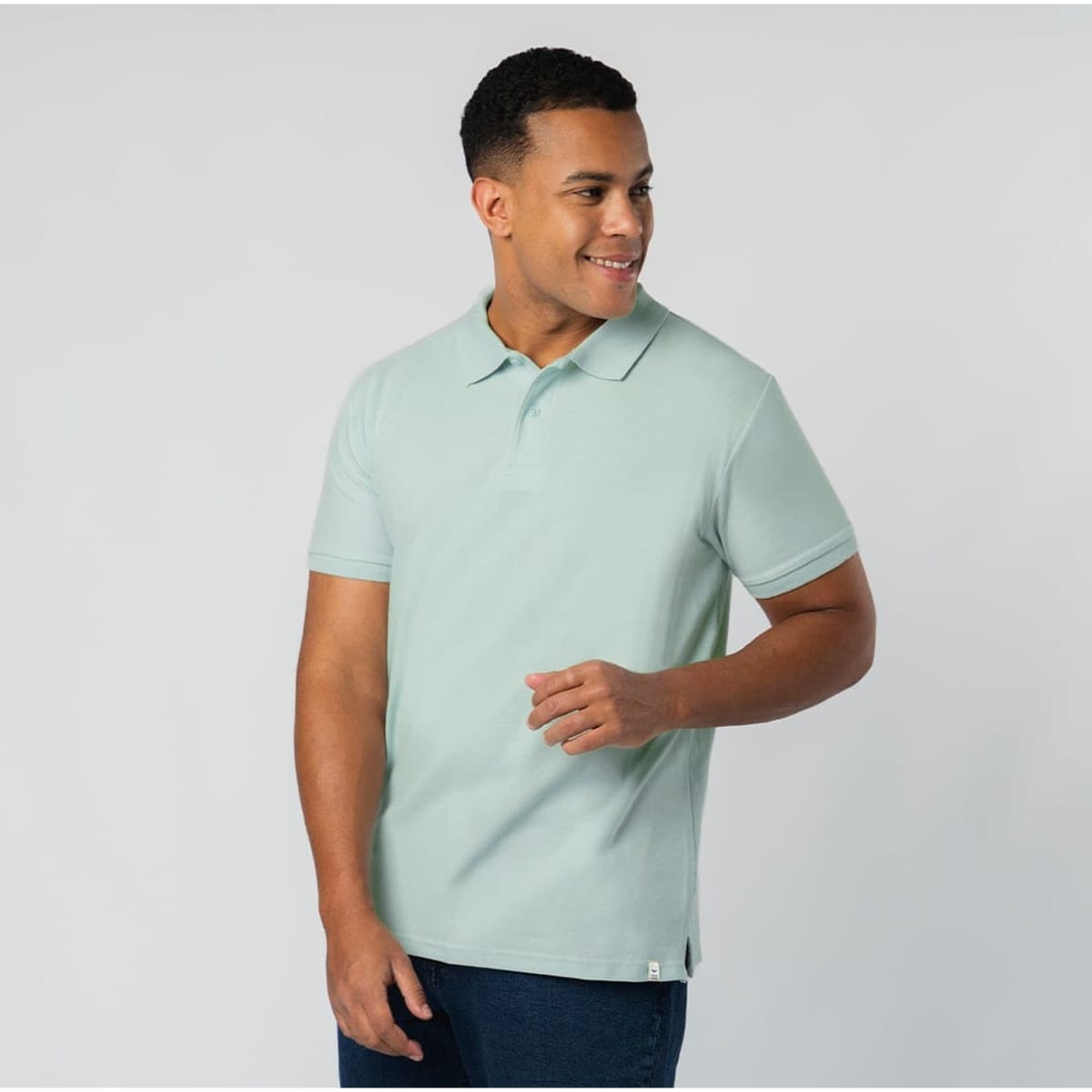 A light green polo shirt on a smiling model. The shirt features a small logo.
