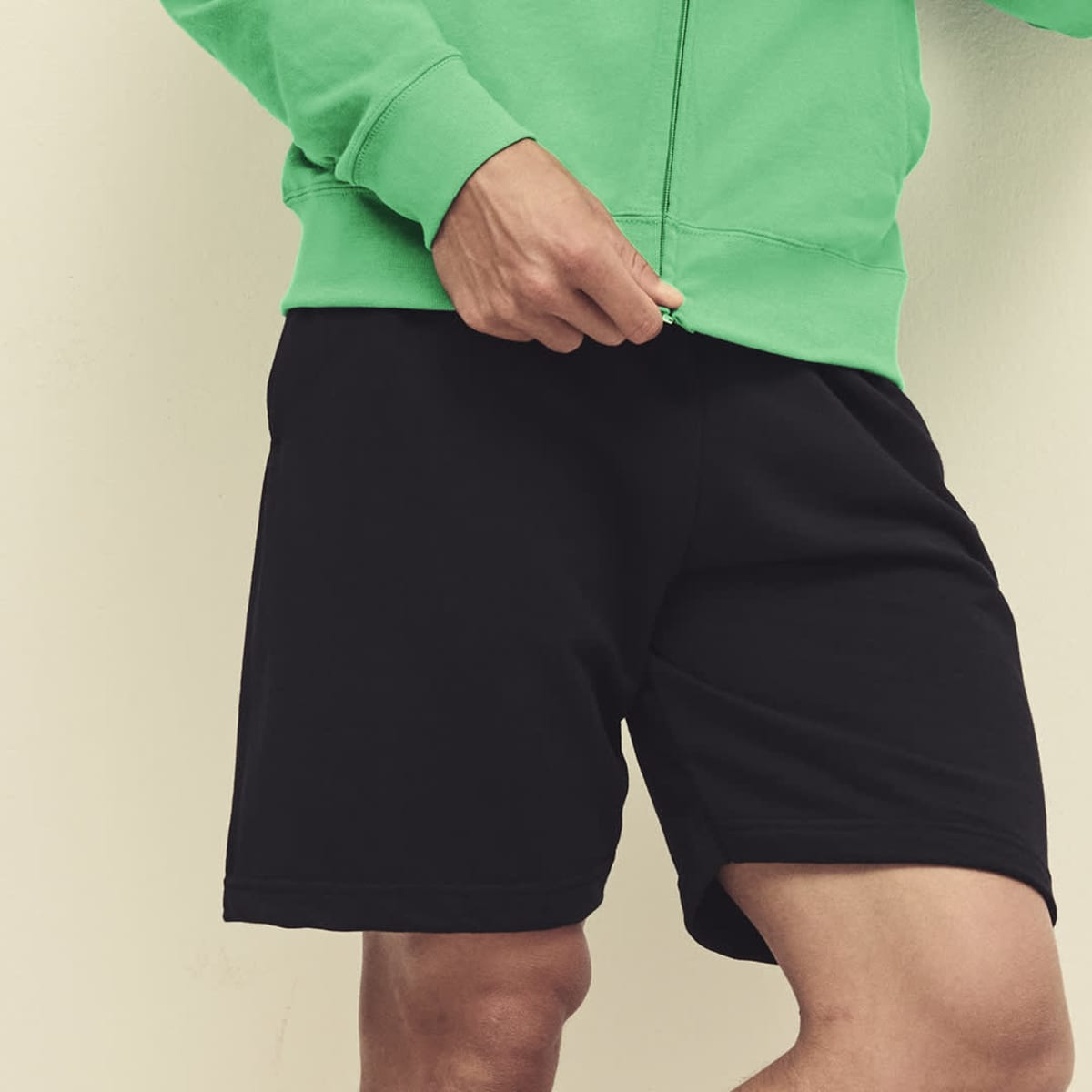 Lightweight black sports shorts paired with a bright green hoodie, featuring a logo on the clothing.