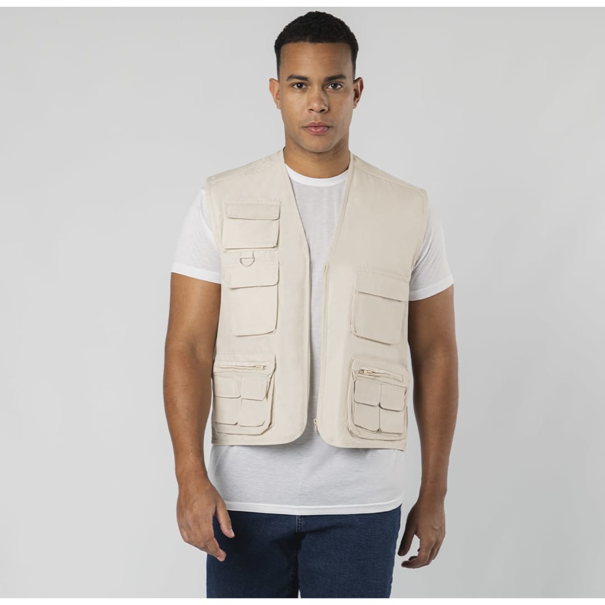 A beige vest with multiple pockets, worn over a white T-shirt. The model stands against a plain background.