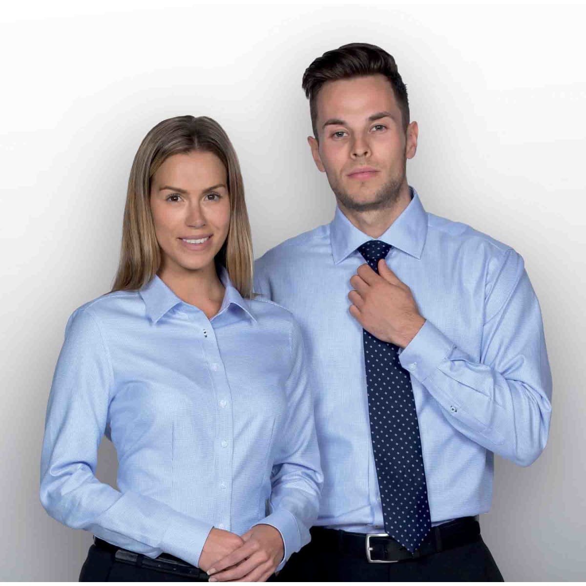 A light blue button-up shirt for women, featuring a collar, paired with a male model in a matching light blue shirt and tie.