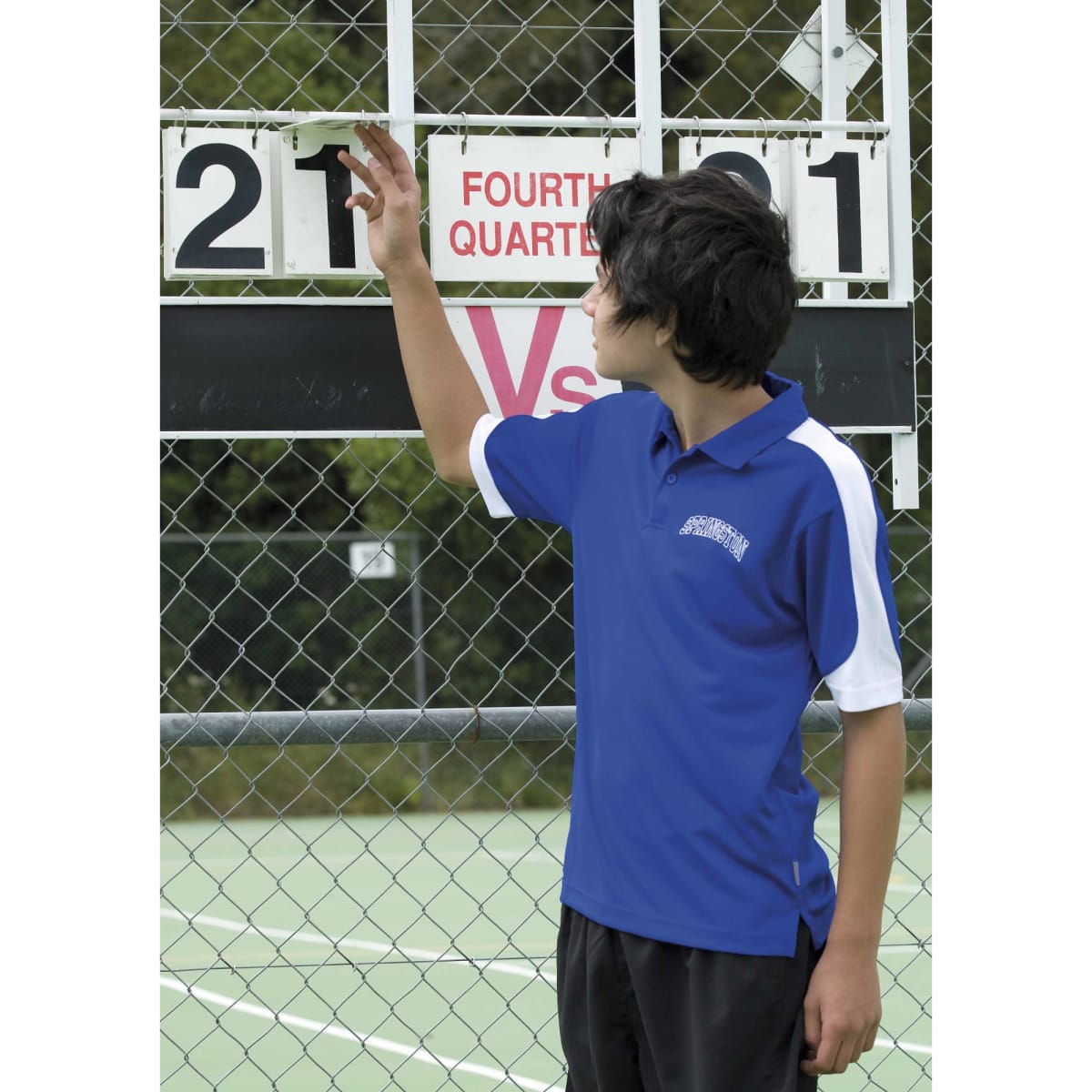 A young person adjusts a scoreboard while wearing a blue and white polo shirt with a logo.