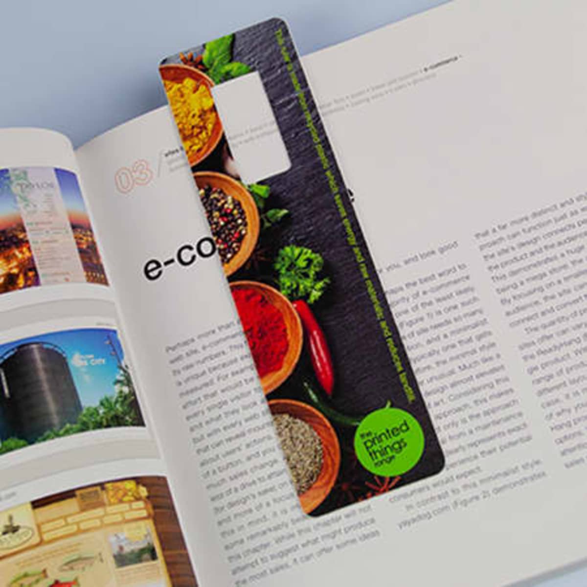 A colourful bookmark featuring spices and herbs design, made from recycled materials, with a logo in the corner.