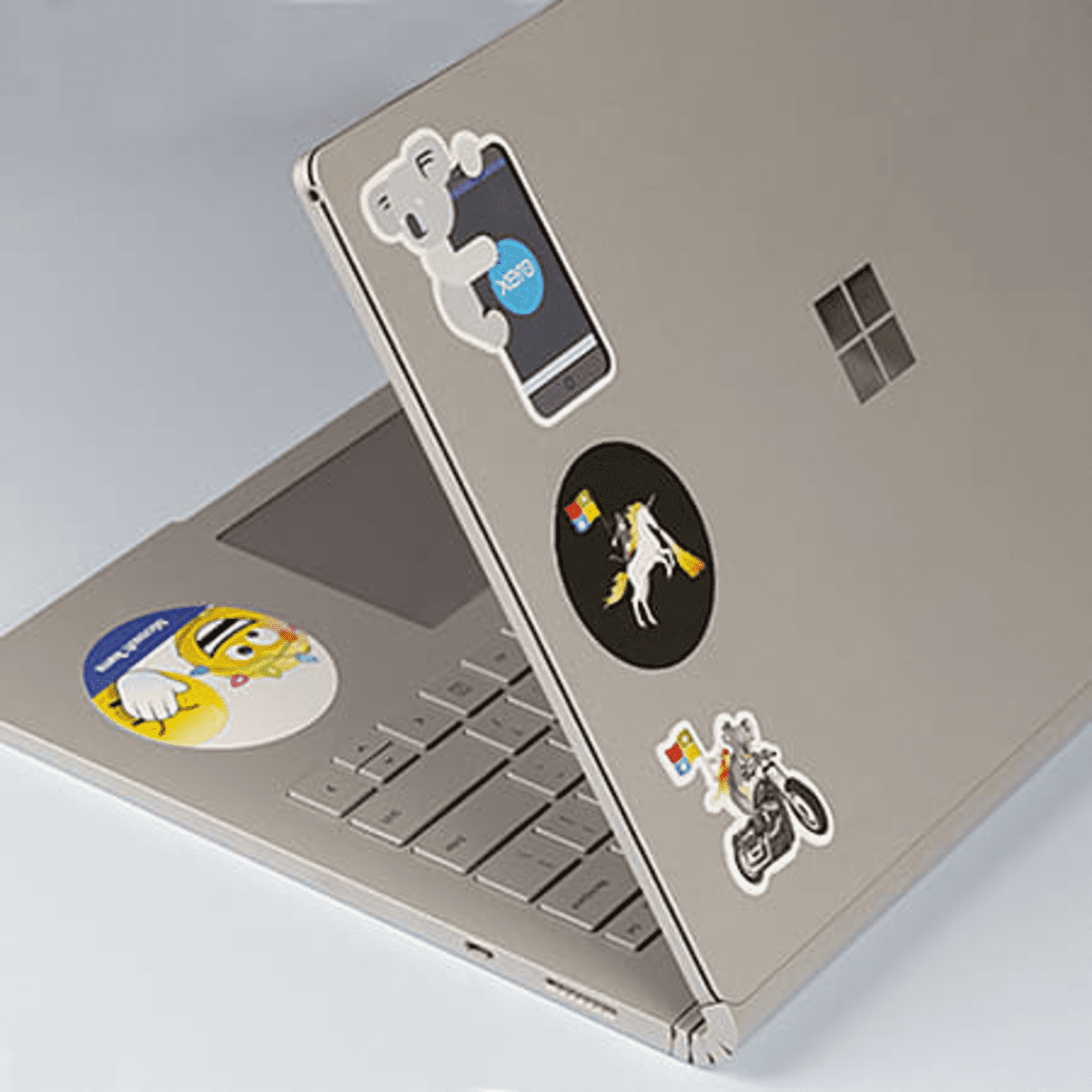 A silver laptop covered in various colourful stickers, including cartoon characters and logos.