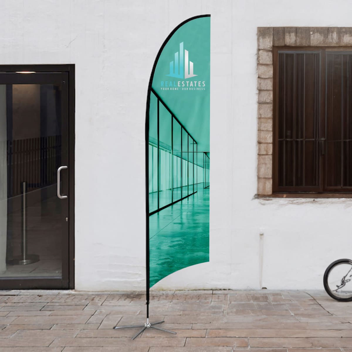 A medium feather flag kit with a teal design, featuring a logo, set up outdoors.