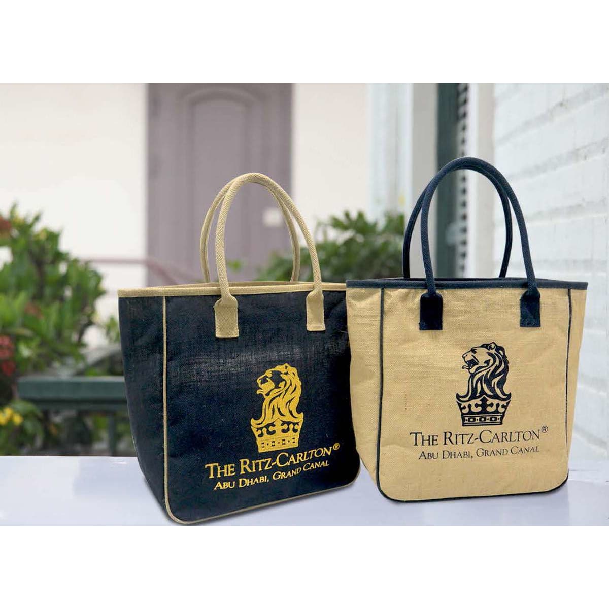Two jute bags are displayed, one in navy blue and the other in beige, each featuring a logo.