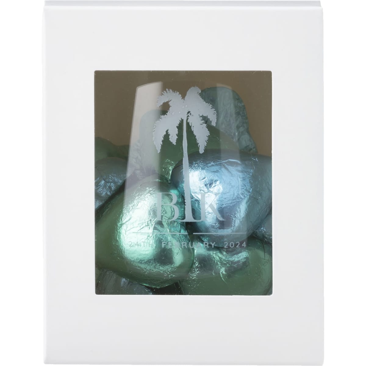 A stemless wine glass in a white gift box, featuring chocolates wrapped in silver and green foil.