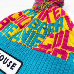 A colourful beanie featuring a mix of bright pink, yellow, and turquoise with a pom pom on top and a logo.