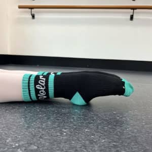 A pair of crew-length socks featuring black and teal colours, with a logo design on the black band.