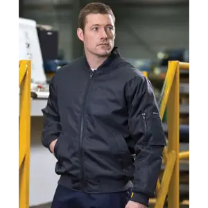 A man wears a black jacket with a zipper and side pockets, featuring one with a logo on the sleeve.