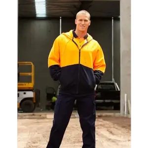 A man wearing a high-visibility orange and navy full zip fleece hoodie, posed in an industrial setting.