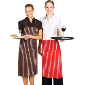 Two women are wearing striped full bib aprons, one in brown and the other in red, holding a plate and a tray.