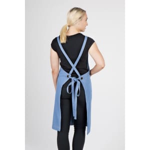 A full body denim apron in blue, featuring adjustable straps and a tied waist, displayed on a model from the back.