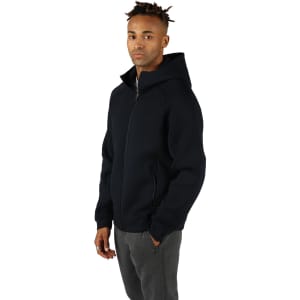 A black men's hoodie with a zip and a hood, featuring side pockets and a logo. The model is wearing grey pants.