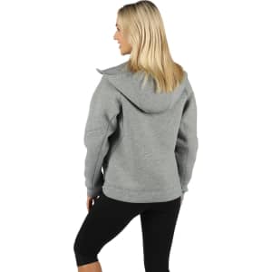 A grey women's junior hoodie with a large hood, featuring a logo, worn with black leggings.
