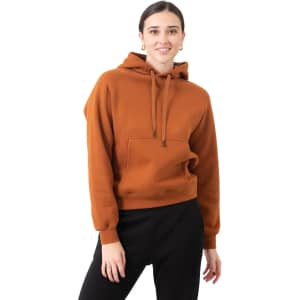 A brown kangaroo pocket hoodie featuring a relaxed fit and drawstring hood, modelled by a woman.