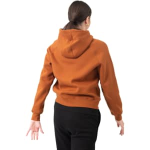 A woman wearing a rust-coloured hoodie with a kangaroo pocket, viewed from the back. The hoodie has a logo.