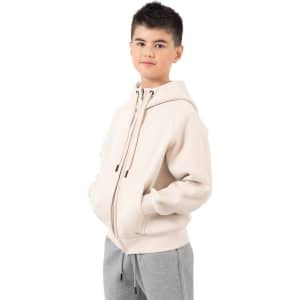 A light beige hoodie with a kangaroo pocket and zipper, featuring a logo. The model wears grey pants.