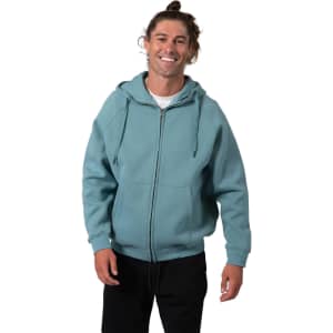 A man wearing a blue-green zip-up hoodie with a kangaroo pocket, smiling and standing against a white background.
