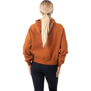 A half-zip jumper in earthy orange, featuring a hood and relaxed fit, with a visible logo.