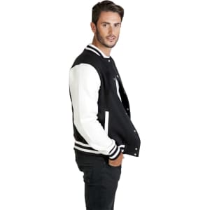 A men's varsity jacket in black with white sleeves, featuring a logo. Model is posing in profile.