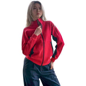 A woman wearing a red jacket with black accents, featuring a zippered front and a logo on the sleeve.