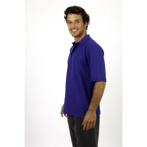 A man smiling while wearing a blue regular pique knit polo shirt, paired with grey pants.