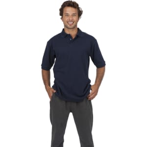 A man wearing a navy blue cotton pique knit polo shirt, smiling and posing with hands in pockets.