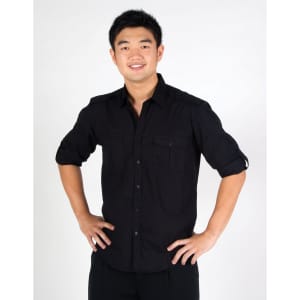 A black long sleeve button-up shirt with two front pockets, worn by a smiling individual posing with hands on hips.