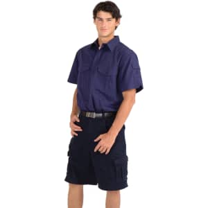 A navy cotton drill short sleeve work shirt with two front pockets, worn by a model paired with dark shorts.