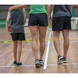 A group of three people wearing men's black FLEX shorts, standing on a basketball court from behind with a basketball.
