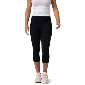 Black high-rise 3/4 leggings worn by a model, paired with a fitted white top and white sneakers.