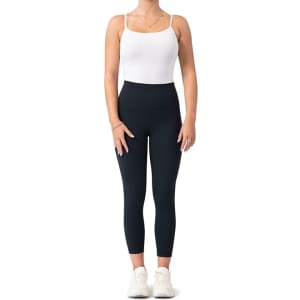 High-rise full-length leggings in black, paired with a white tank top and white sneakers. The model is standing upright.
