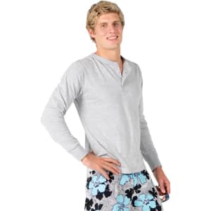 A grey long-sleeve men's t-shirt features a round neckline and a logo. The model wears patterned swim shorts.