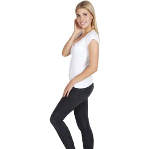 A woman wearing a fitted white Hanley T-shirt and black jeans, standing in a side pose. The shirt has a logo.