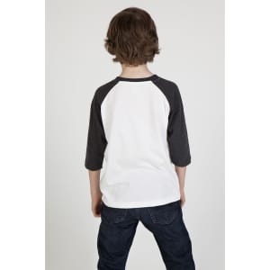 A back view of a kid wearing a white and dark grey 3/4 raglan sleeve t-shirt, paired with dark blue jeans.