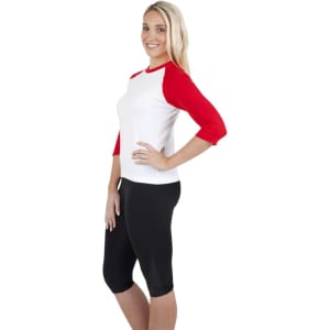 A woman stands wearing a white and red women's 3/4 sleeve raglan t-shirt paired with black leggings.