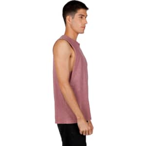 A men's stone wash tank in a muted pink hue, featuring a sleeveless design and a logo on the side.
