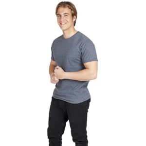 A man wearing a grey heavy marl T-shirt and black trousers, smiling and standing with arms crossed.