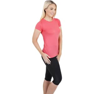 A woman models a short-sleeved, coral pink American style T-shirt paired with black leggings. The shirt features a logo.