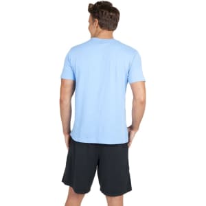 A light blue unisex t-shirt displayed on a model, paired with black shorts and featuring a logo.