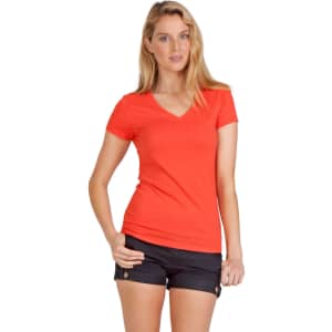 A model wearing an orange V-neck T-shirt paired with black shorts and sandals, standing against a plain background.
