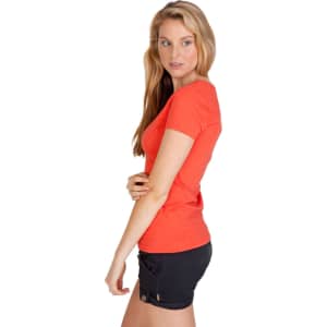 A side view of a woman wearing an orange marl V-neck T-shirt with black shorts. The shirt has a subtle texture and a logo.
