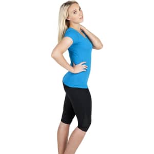 A woman in a blue raw cotton wave T-shirt poses sideways, wearing black leggings. The shirt has a logo.